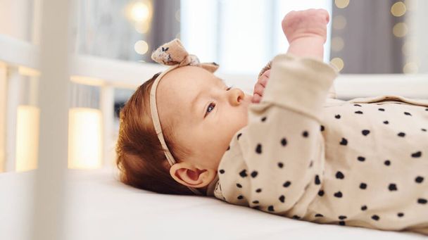 Cute newborn baby lies down indoors in the bed at daytime. - 写真・画像