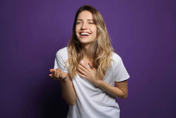 Cheerful young woman laughing on violet background - Photo, image