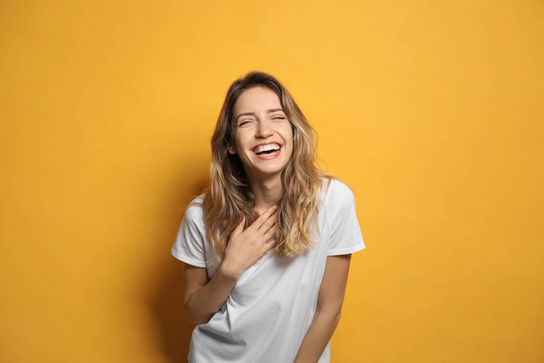 Cheerful young woman laughing on yellow background - Fotoğraf, Görsel
