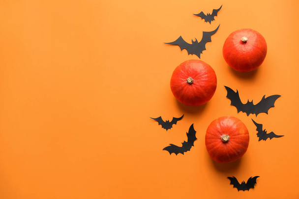 Flat lay composition with pumpkins and paper bats on orange background, space for text. Halloween decor - Фото, изображение