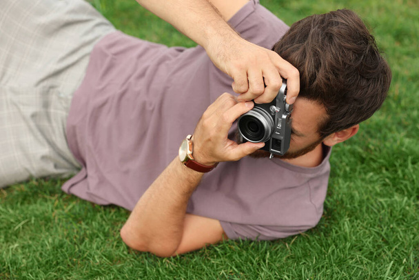 Man with camera taking photo on green grass. Interesting hobby - Photo, Image