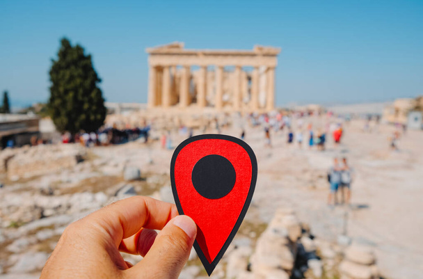 Yunanistan 'ın başkenti Atina' daki ünlü Partenon 'un kalıntılarını gösteren kırmızı bir işaret taşıyan bir adam, turistlerle dolu. - Fotoğraf, Görsel