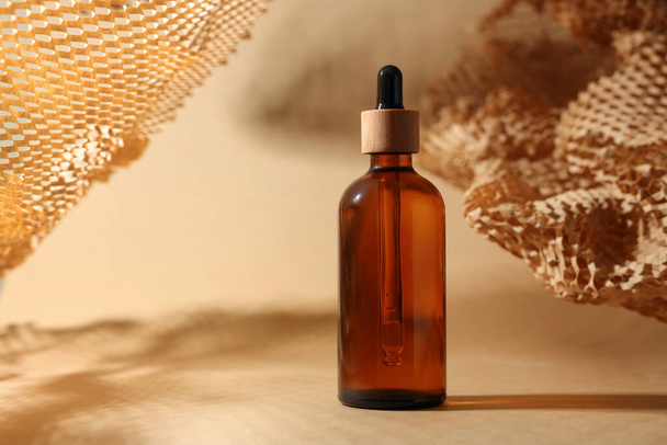 Glass bottle of essential oil on dark beige background, space for text - Valokuva, kuva