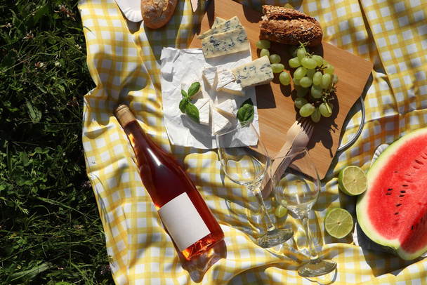 Picnic blanket with delicious food and wine on green grass outdoors, top view - Fotografie, Obrázek