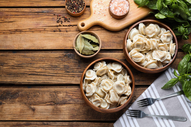 Tasty dumplings in bowls served on wooden table, flat lay. Space for text - Photo, Image