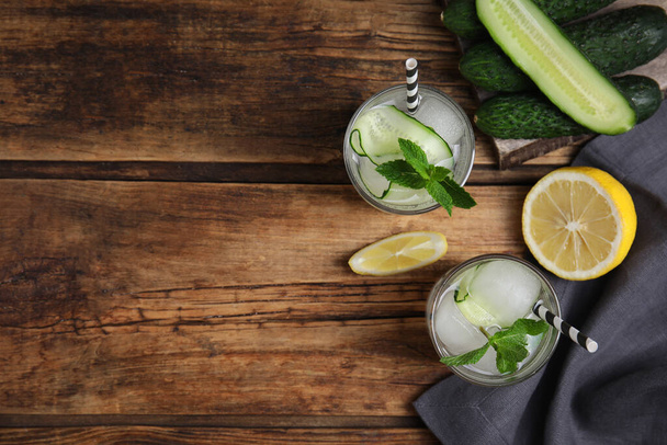 Tasty fresh cucumber water and ingredients on wooden table, flat lay. Space for text - Fotó, kép