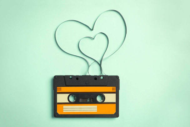 Music cassette and hearts made with tape on turquoise background, top view. Listening love song - Фото, зображення