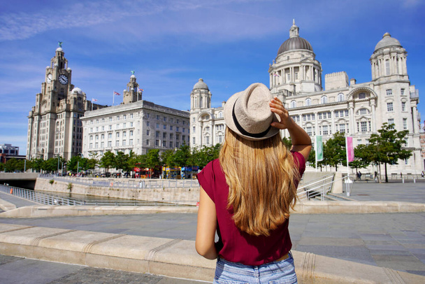 Vakantie in Liverpool, Verenigd Koninkrijk. Mooie jonge vrouw op bezoek bij Pier Head met "The Three Graces" in het centrum van Liverpool, Engeland. - Foto, afbeelding