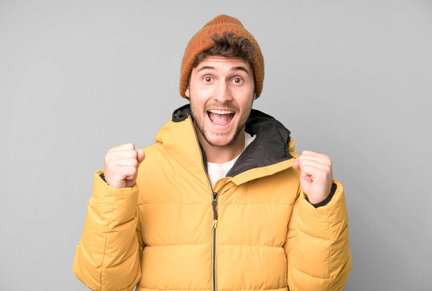 handsome teenager feeling shocked,laughing and celebrating success. winter clothes and cold concept - Fotoğraf, Görsel
