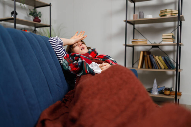 Холодна жінка з гарячкою лежить на дивані. Дівчинка хвора на сезонний грип
 - Фото, зображення