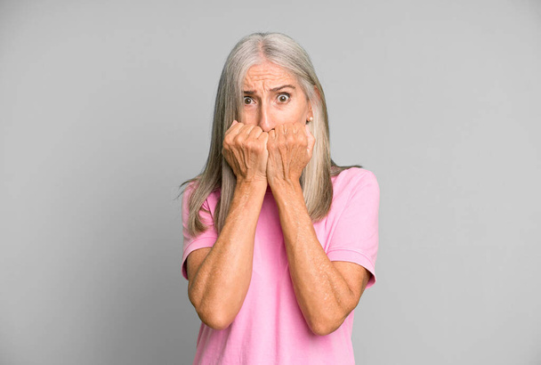 pretty gray hair senior woman looking worried, anxious, stressed and afraid, biting fingernails and looking to lateral copy space - Foto, Imagem