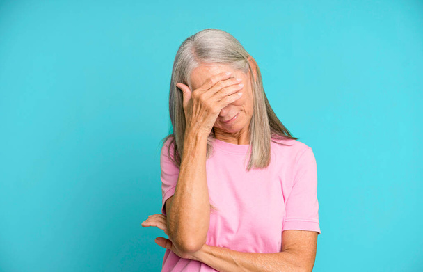 pretty gray hair senior woman looking stressed, ashamed or upset, with a headache, covering face with hand - Foto, Imagen