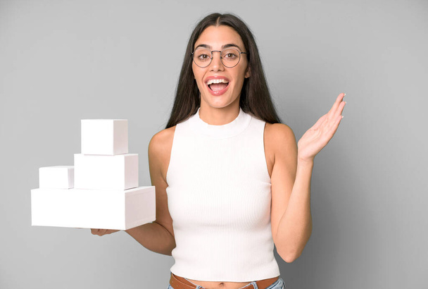hispanic pretty woman feeling happy and astonished at something unbelievable with white blank different boxes - Foto, immagini