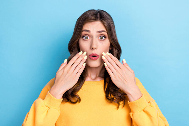 Photo portrait of adorable young woman palms cover mouth confused tell secret wear trendy yellow outfit isolated on blue color background. - Fotó, kép