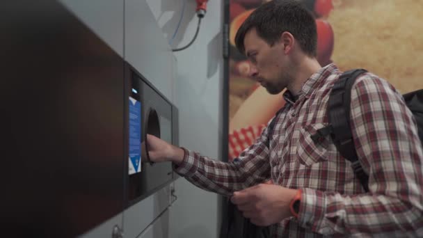 Hombre devuelve botellas de plástico, contenedores reutilizables para revertir la máquina expendedora en Munich, Alemania supermercado. Hombre usando el punto de depósito de botella. Máquina automática de reciclaje de botellas para recogida de plástico.  - Metraje, vídeo