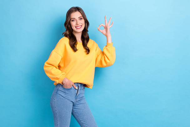 Photo of young nice gorgeous adorable pretty cute woman wear yellow shirt showing okey sign toothy smile positive isolated on blue color background. - 写真・画像