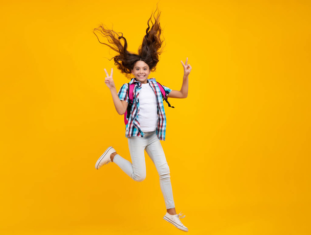 School teen girl in with backpack. Teenager student on isolated background. Run and jump. Kids learning, education, studying and knowledge - Фото, изображение