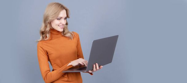 Happy woman use modern laptop computer technology grey background, internet surfing. Woman portrait, isolated header banner with copy space - Photo, image