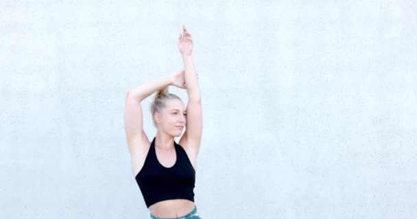 Schöne junge blonde Fitness-Frau trägt Blazer und blaue Sportkleidung Stretching und Ganzkörperwärmung in der Früh. Sportliche Frau beim Aufwärmtraining an der Wand. Hochwertiges 4k Filmmaterial - Filmmaterial, Video