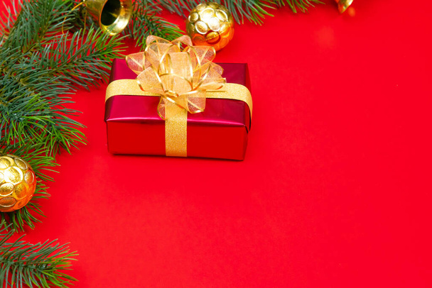 Concepto de fondo de Navidad. Vista superior de la caja de regalo de Navidad bolas de oro con ramas de abeto y campana sobre fondo rojo. - Foto, imagen