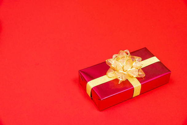 Noel concept de fond. Vue du dessus de la boîte cadeau de Noël boules d'or avec branches d'épinette et cloche sur fond rouge. - Photo, image