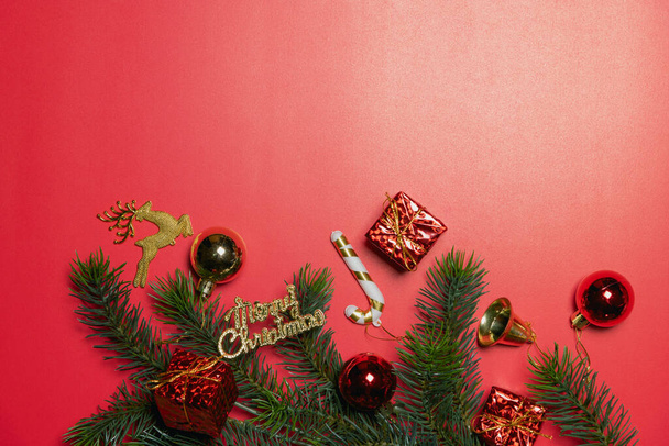 クリスマスの背景概念。赤い背景にスプルースの枝と鐘のあるカラフルなボールクリスマスギフトボックスのトップビュー. - 写真・画像