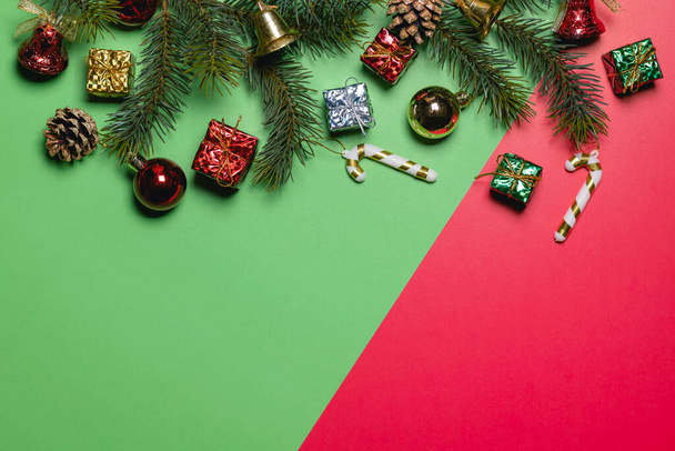 Weihnachten Hintergrundkonzept. Bunte Kugeln mit Fichtenzweigen und Glocke auf rotem und grünem Hintergrund. - Foto, Bild