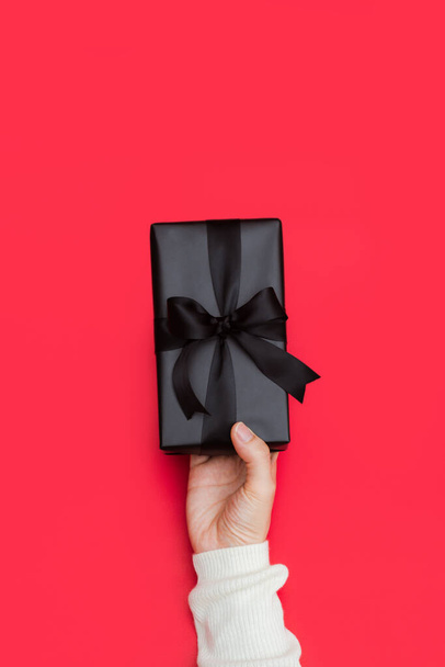 Close up shot of female hands holding a small gift wrapped with black ribbon. Holiday present concept with copy space, banner. - Fotografie, Obrázek