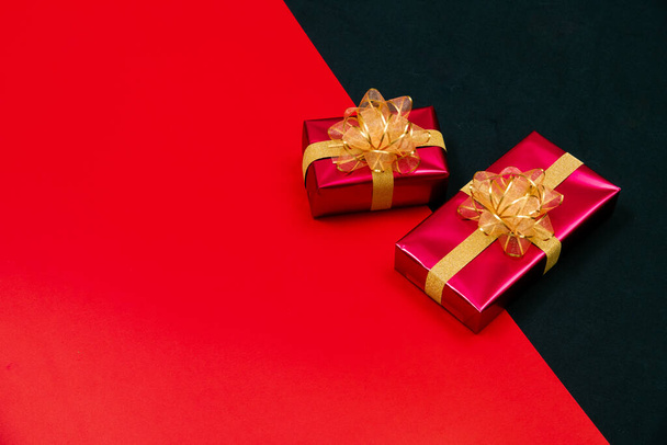 Draufsicht auf schwarze Geschenkbox mit roten und schwarzen Bändern isoliert auf rotem und schwarzem Hintergrund. Einkaufskonzept Boxtag und Black Friday - Foto, Bild