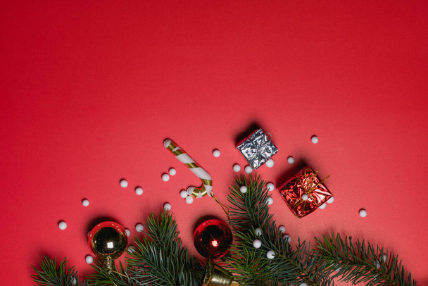 Concepto de fondo de Navidad. Vista superior de la caja de regalo de Navidad bolas de colores con ramas de abeto y campana sobre fondo rojo. - Foto, imagen