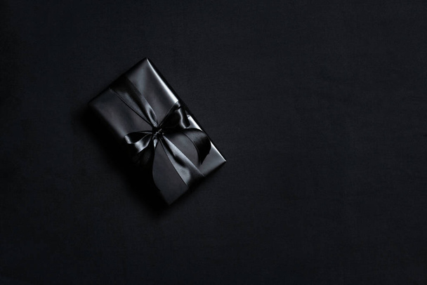 Top view of black gift box with black ribbons isolated on black background. Shopping concept boxing day and black Friday sale composition. - Foto, afbeelding