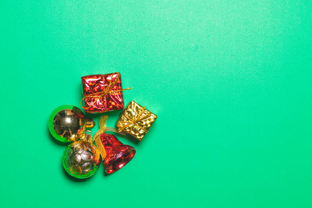 The concept of the new year, christmas. Top view of Christmas gift box red balls with spruce branches and bell on green background. - Photo, Image