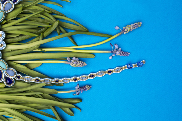 Collane Soutache bijouterie blu con pietre blu e cristalli azzurri e ciano sullo sfondo ciano di steli d'erba
 - Foto, immagini