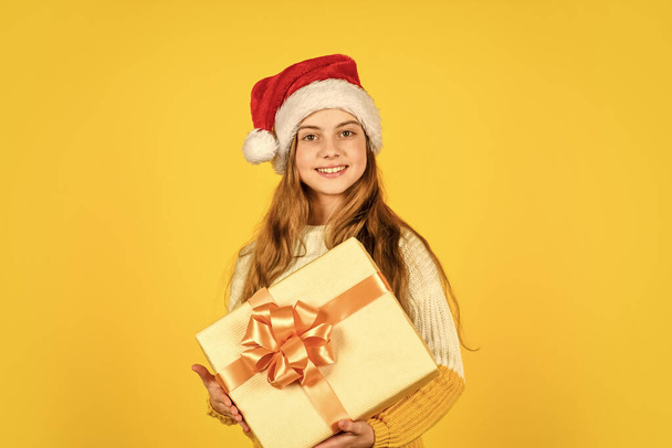 my present. xmas party celebration. happy new year. christmas shopping online. time for discount. smiling kid hold purchase. presents and gifts from santa claus. small girl santa at yellow background. - Zdjęcie, obraz