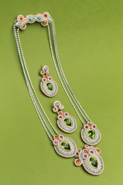 Ensemble bijouterie Soutache boucles d'oreilles et colliers colorés avec cyan violet vert et cristaux roses sur fond vert
 - Photo, image