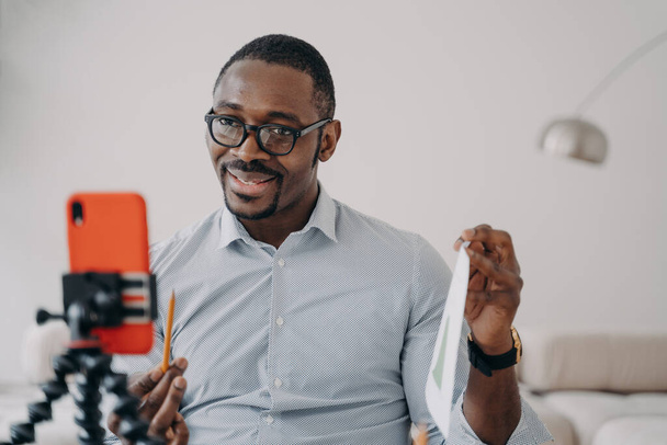 Afrikkalainen amerikkalainen liikemies esittelee liikeprojektin videopuhelulla älypuhelimella. Hymyilevä musta mies liiketoiminnan valmentaja tallennus oppimisen webinar tai konsultointi asiakkaan verkossa etänä. - Valokuva, kuva