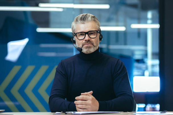 Video call, serious and mature businessman looking thoughtfully at camera, gray-haired man using headset for remote communication and online meeting. - Fotoğraf, Görsel