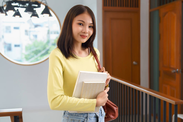 Conceito de educação e alfabetização, estudante universitário menina sorriso enquanto carrega saco e segurando livro didático. - Foto, Imagem