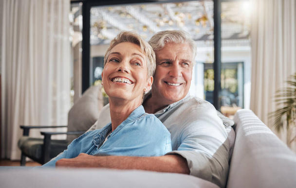Liebe, Paar und Ruhestand mit einer älteren Frau und einem Mann auf einem Sofa, um gemeinsam in ihrem Haus zu entspannen. Glücklich, lächelnd und nachdenkend mit einem älteren Rentner im Wohnzimmer eines Hauses. - Foto, Bild