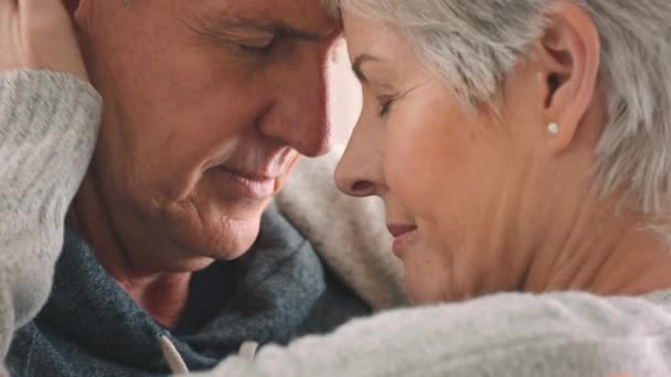 Volwassen paar, liefde en band met het voorhoofd aanraken in de huiskamer of thuis interieur. Zoom in op gezicht, veiligheid of vertrouwen man en oudere of oudere vrouw ter ondersteuning, comfort en veiligheid bij pensionering. - Video