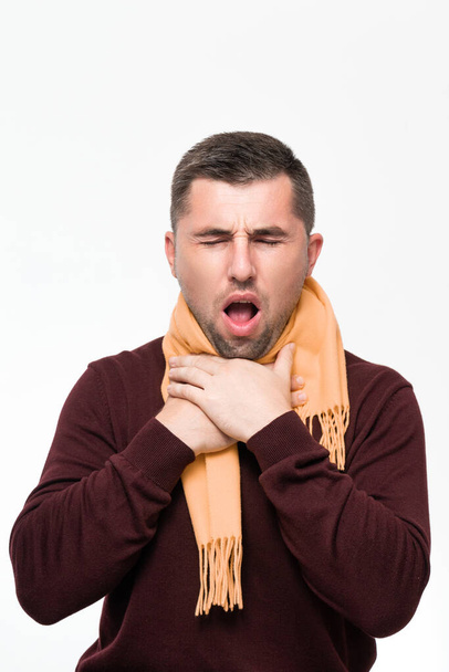 A man suffers from a sore throat, a man wrapped his throat with a scarf, portrait on a white background, severe sore throat. - Photo, image