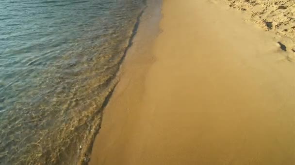 Primo piano della spiaggia di sabbia turchese con acque limpide di Mylopotas in Ios Grecia - Filmati, video