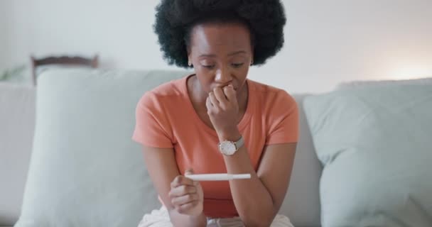 Stressz, ijedt nő otthoni terhességi teszt néz szomorú a nem tervezett baba, egészségügyi kockázat vagy meddőség. Szorongás, félelem vagy aggódó fekete nő várja eredmények terhes tesztkészlet egy kanapén. - Felvétel, videó