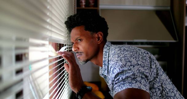 Afrikai férfi néz be az ablakon redőnyök - Fotó, kép