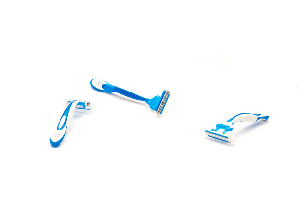 Κοφτερά πλαστικά ξυραφάκια μιας χρήσης με εργονομική λαβή που απομονώνονται σε λευκό φόντο. Ολοκαίνουργιο μπλε και άσπρο ξυράφι με χαλύβδινες λεπίδες - Φωτογραφία, εικόνα