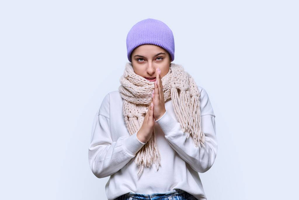 Winter headshot portrait of young female in hat sweater scarf. Adorable beautiful cute teenage girl looking at camera on light studio background. Cold season New Year Christmas holidays fashion beauty - Foto, imagen