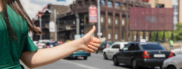 Wkman Hand in einer Geste des Trampens auf dem Hintergrund einer Straße - Foto, Bild