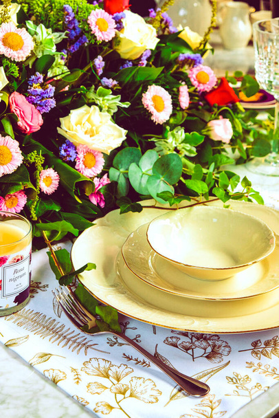 Güzel bir tabak ve mükemmel renkte çiçekler lüks bir masada duruyor. - Fotoğraf, Görsel