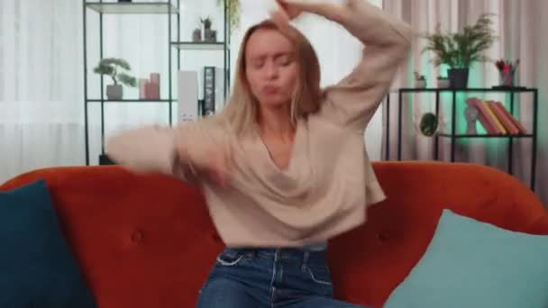 Overjoyed delighted caucasian adult girl showing rock n roll gesture by hands, cool sign, shouting yeah with crazy expression, dancing, emotionally rejoicing in success. Young woman at home apartment - Materiaali, video