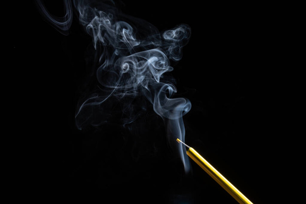 A yellow colored pencil touching the white smoke coming from below. Close up. Sharp pencil scraps. - Zdjęcie, obraz